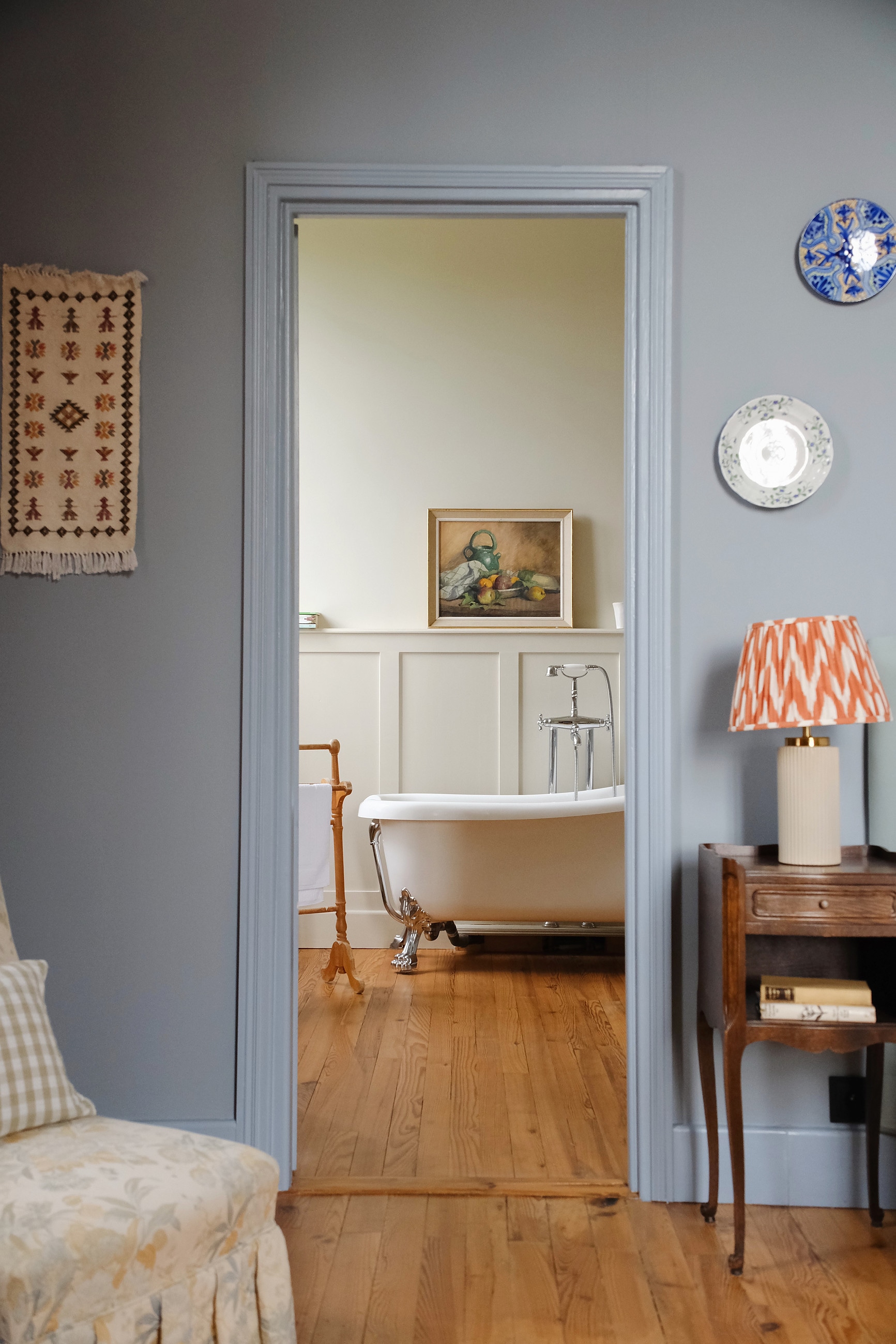 Pale blue bedroom looking through a doorway to a roll top bath, the Château at Pomiro