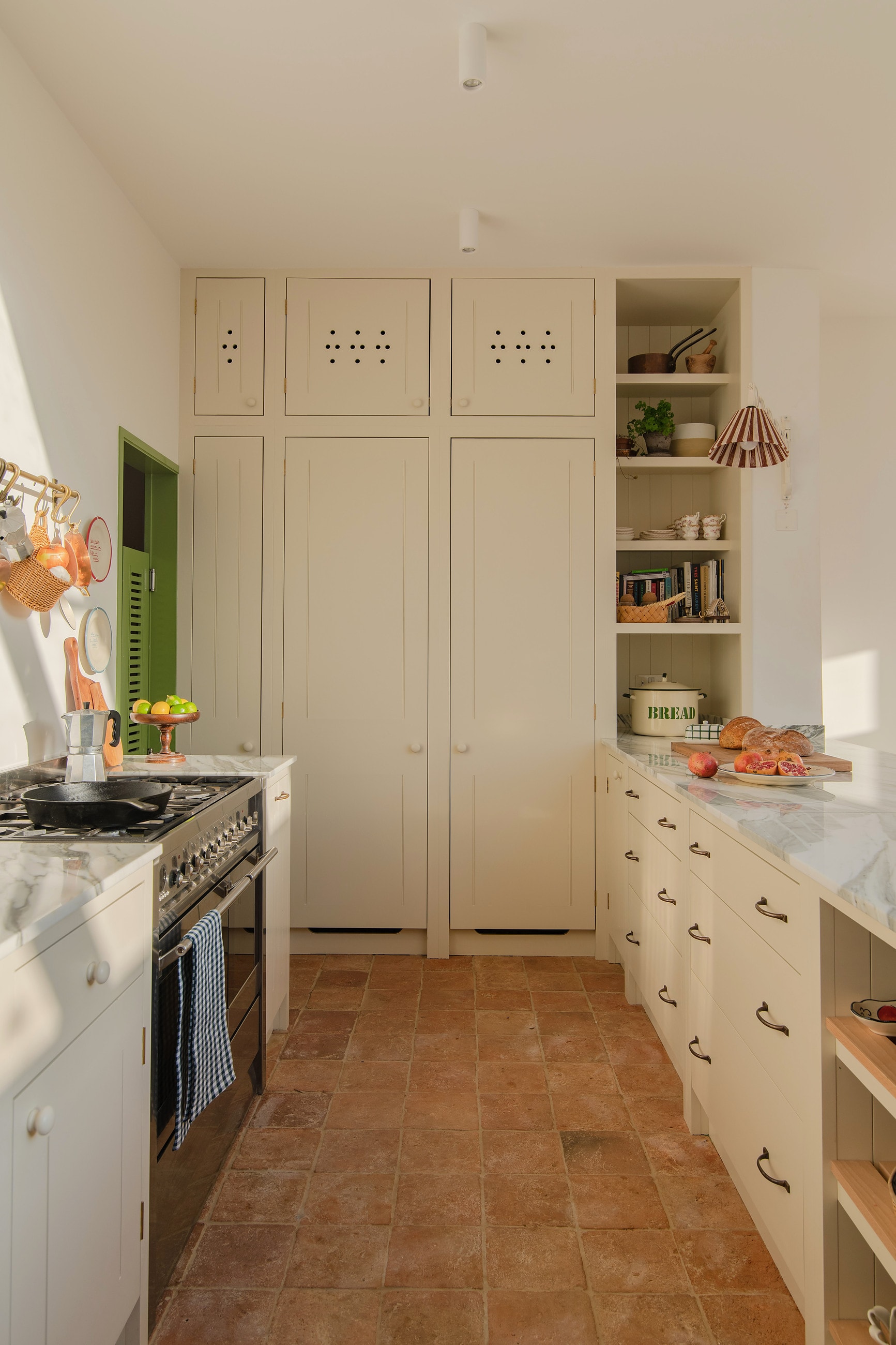 Cream pantry with marble worktops and a terracotta tiled floor