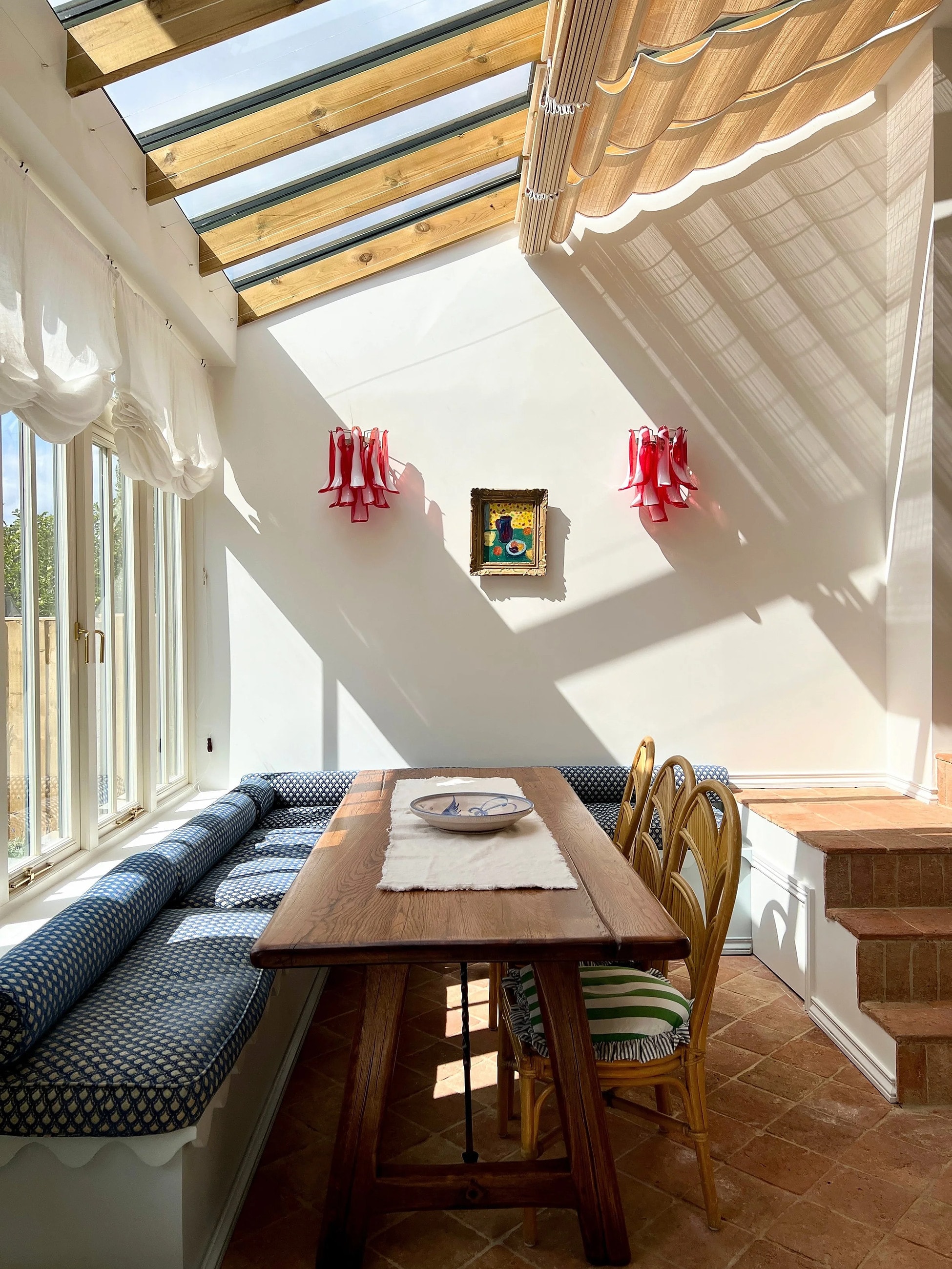 Garden room with a long table, banquette seating and skylights