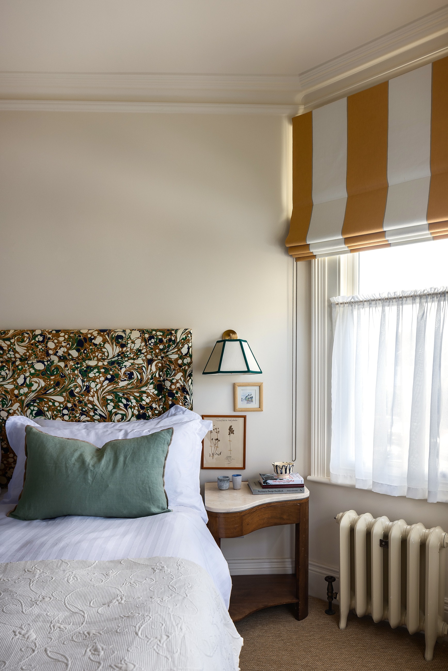 Bedroom with a floral headboard and ochre striped blind